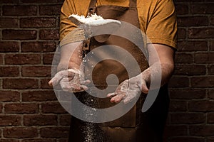 Flying pizza dough with flour scattering in a freeze motion of a cloud of flour midair on black. Cook hands kneading dough. copy