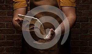 Flying pizza dough with flour scattering in a freeze motion of a cloud of flour midair on black. Cook hands kneading dough. copy