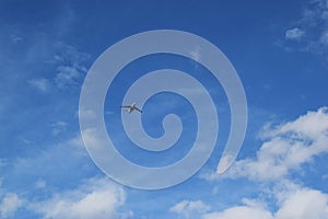 flying plane against the blue sky with white clouds.