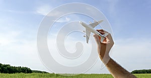 Flying plane on the blue sky banner background. A toy plane in hand flies to travel. Summer, vacation, travel
