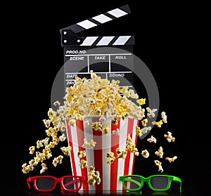 Flying popcorn and film clapper board isolated on black background