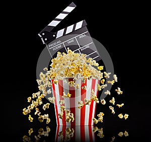 Flying popcorn and film clapper board isolated on black background