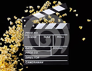 Flying popcorn and film clapper board isolated on black background