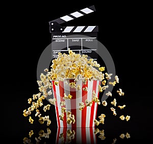 Flying popcorn and film clapper board isolated on black background