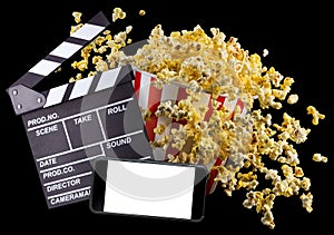 Flying popcorn, film clapper board and phone isolated on black background