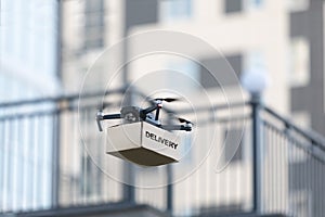 Flying quadrocopter carrying paper box on city blurred background