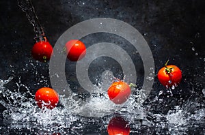 Flying red tomatoes in water drops on a gray background