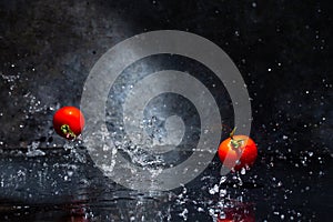 Flying red tomatoes in water drops on a gray background