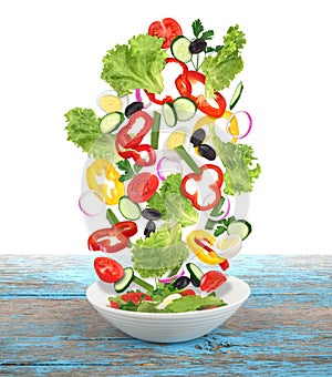 Flying salad with plate on wooden table