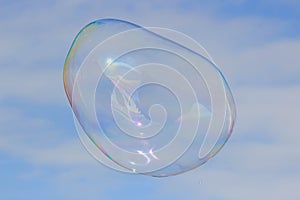 Flying soap bubble with reflection of the blue sky
