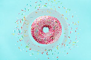 Flying sprinkled pink donut. Sweet doughnut on pastel blue background photo