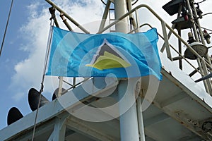 Flying St Lucia flag, a blue field with a central triangle, on the wind hanging on the navigational mast.