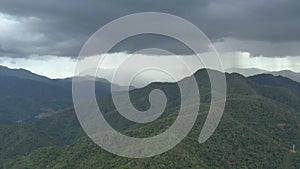 Flying through the stormy day above green mountain tops. 4K aerial view of rainforest