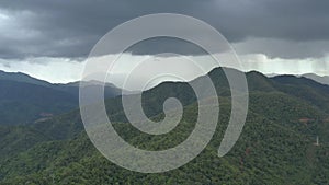 Flying through the stormy day above green mountain tops. 4K aerial view of rainforest