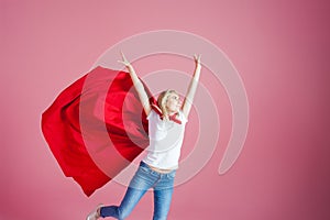 Flying superhero. Funny young woman in the image of a superhero to the rescue. Pink background