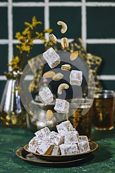 flying traditional Turkish delight (lokum) with nuts and arabic tea, gypsophila vase.