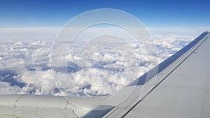 Flying and traveling abroad, view from airplane window on the wing on cloudy blue sky aboard morning winter time, journey