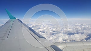 Flying and traveling abroad, view from airplane window on the wing on cloudy blue sky aboard morning winter time, journey