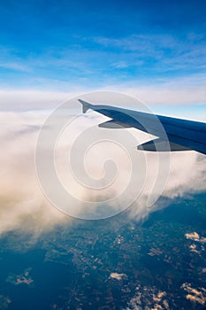 Flying and traveling, view from airplane window on the wing on sunset time. Aircraft wing under the earth and clouds. Flight in