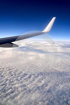 Flying and traveling. View of airplane wing on blue sky background. Plane over clouds in the sky.