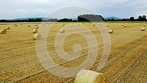 Flying up over a stubble field with hay rolls