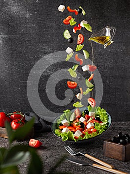 Flying vegetables are the ingredients of a Greek salad. On a dark background with props