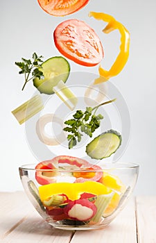 Flying vegetables in a plate for salad on white background