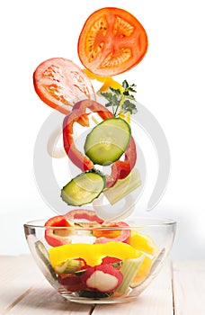 Flying vegetables in a plate for salad on white background