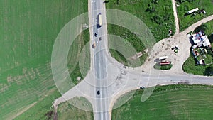 Flying vertically above car driving on road 4K. Aerial shot from top of car vehicle driving on countryside with green