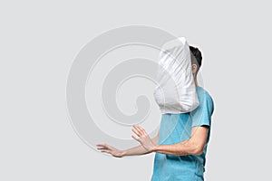 Flying white pillow hitting pretty brunet man in a blue tee.