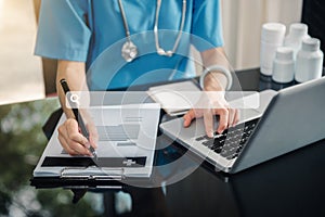 Fmale doctor hand working on laptop computer, browsing internet or medical research on desk in doctor office, close up. Medical