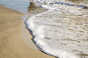 Foam from the ocean wave that washes the sand on the sea beach