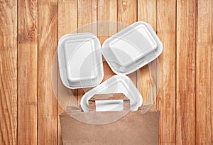 Foam plastic containers with delicious food on wooden background