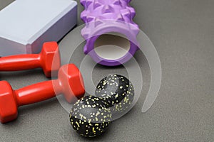 Foam rollers, dumbbells and yoga block on grey mat with massage roller. Set of fitness equipment on a gray background, front view