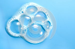 Foam soap bubbles on blue background. Liquid soap bubble, Froth background, top view. Soap foam popping