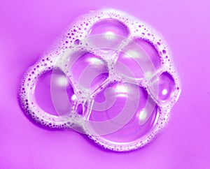 Foam soap bubbles on purple background. Liquid soap bubble, Froth background, top view. Soap foam popping