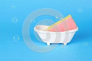 Foam sponge in a stand in the form of a bathtub on a blue background