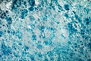 Foam on surface of liquid blue detergent household chemicals, big and small foamed bubbles, close-up full depth of field, top view