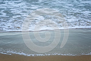 Foam wave on the sandy shore. Relaxation at the resort and activity in nature. Background. Space for text