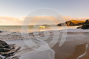 A sandy Cornish beach bathed in a golden glow as the sun begins to set