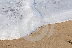 Foaming breaking wave and backwash foam on a sandy shoreline