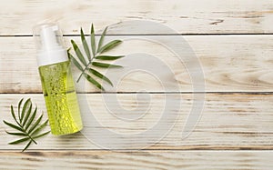 Foaming facial cleanser and cotton pads on wooden background, top view