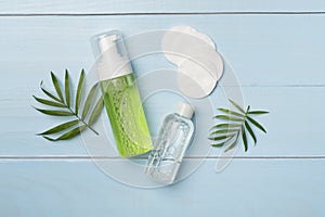 Foaming facial cleanser and micellar water on wooden background, top view