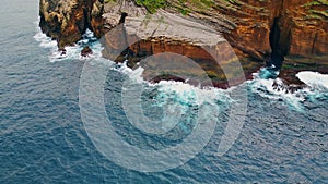 Foaming waves crashing rocky coastline aerial. Wild sea washing reef rock cliffs