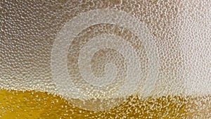 Foamy beer sizzling bubbling transparent glass closeup.Blebs froth raising up