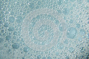 Foamy cosmetic texture with bubbles on blue background. Cleanser, shampoo, wash - liquid soap, shower gel, hyaluronic