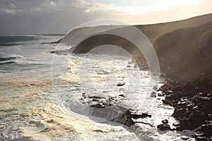 Foamy sea at rocky coast with sunshine