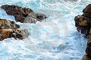 Foamy sea water flows through the stones