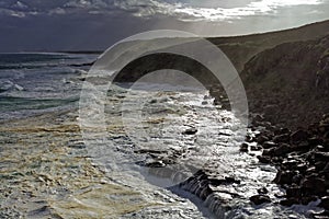 Foamy sea by wild waves at rocky coast landscape