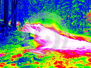 Foamy water level of waterfall, curves between boulders of rapids. Water of mountain river in infrared photo. Amazing thermography